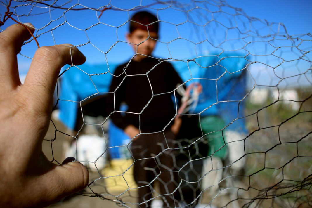 Refugee kid behind wire fence